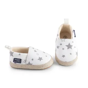 Primer plano de zapatos de bebé blancos con estampado de estrellas y suela de yute