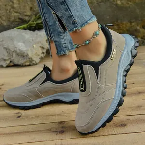Primer plano de zapatos informales de exterior caqui para hombre en suelo de madera.