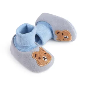 Close-up of soft blue baby booties featuring a cute brown bear embroidery detail