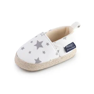 Primer plano detallado de un zapato blanco para bebé con estrellas grises y suela de yute