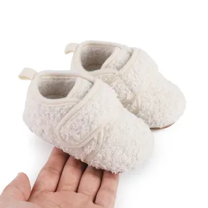 Close-up detail of cozy cream sherpa baby booties held in hand to show size and scale