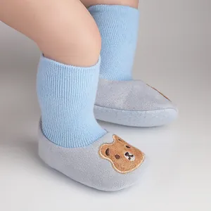 Detailed view of the cute cartoon bear patch on warm blue and grey baby soft sole shoes
