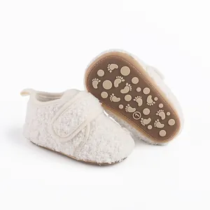 Close-up of cozy white sherpa baby pre-walker shoes with anti-slip rubber soles.
