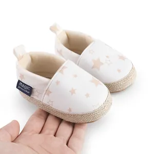 Zapatos de gateo para bebé con suela blanda y patrón de estrellas sostenidos en mano
