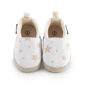 Primer plano de zapatos de lona blanca para bebés con patrón de estrellas beige