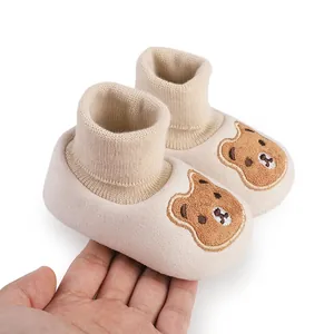 Close-up of beige baby shoes with cute bear patches and soft knit ankle cuffs
