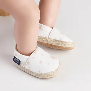 Primer plano detallado de zapatos blancos para bebé con estrellas y suela de yute