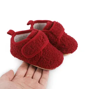 Detail of red fuzzy winter baby shoes with hook-and-loop strap on hand