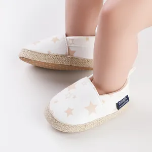 Vista detallada de zapatos de bebé para caminar en lona blanca con patrones de estrellas