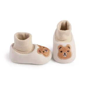 Close-up detail of cute beige soft sole baby shoes with bear embroidery and knit cuff