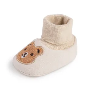 Detailed view of soft beige baby shoe with cute cartoon bear embroidery and knitted cuff
