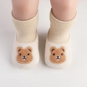 Close-up of baby walker shoes with cute bear embroidery and ribbed socks