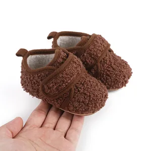 Brown fuzzy baby winter shoes held in hand to show small size and soft texture