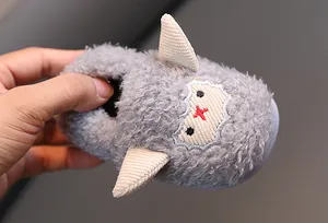 Primer plano de una zapatilla de peluche gris para bebé con cuernos beige y cara bordada