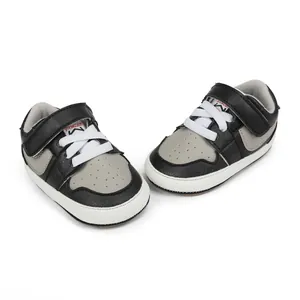 Close-up of black and grey baby walker shoes featuring white laces and secure strap closure.