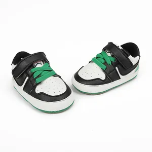 Detailed view of black and white baby sneakers with vibrant green laces and velcro strap