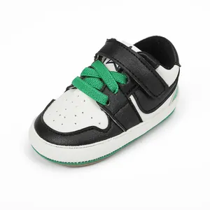 Close-up of black and white baby walking shoe with green laces and velcro strap