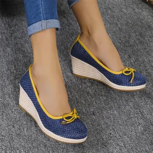 Detailopname van stijlvolle blauw geweven dames sleehakken met geel strikje en bies