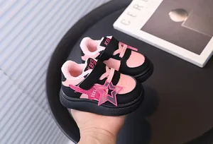 Detail of pink and black children's winter shoes with warm fur lining and star ornament.