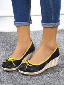 Gedetailleerde close-up van stijlvolle zwarte dames wedge schoenen met gele bies en strik