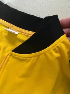 Detalle de chaqueta amarilla casual con cuello alto de canalé negro y cremallera