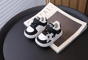 Detail of black and white children's warm sneakers with fleece lining and star charm.