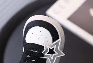 Detail view of children's black and white sneakers with a star-shaped lace ornament.