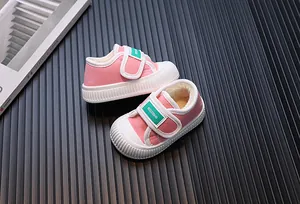 Close-up of pink fleece-lined children's canvas shoes with green velcro straps