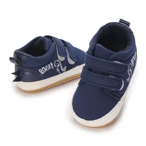 Nahaufnahme von dunkelblauen Baby-Lauflernschuhen mit Klettverschluss und Dino-Motiv