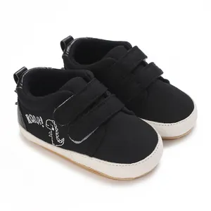 Seitenansicht schwarzer Segeltuch-Lauflernschuhe für Babys mit Dino-Stickerei und Klettverschluss.