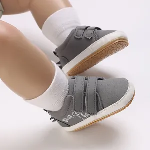 Graue Baby-Lauflernschuhe aus Canvas mit Klettverschluss und rutschfester Sohle.