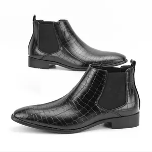 Detailopname van zwarte Chelsea boots van leer met krokodillenmotief en een vierkante neus.