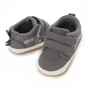 Detailansicht graue Baby-Lauflernschuhe aus Segeltuch mit Dinosaurier-Print und Klettverschluss.