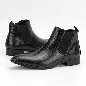 Detailed view of men's black Chelsea boots with crocodile texture and elastic side