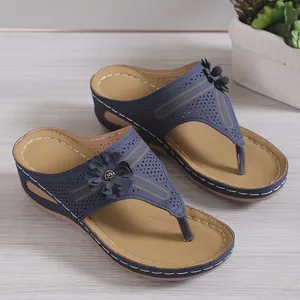 Detailansicht der dunkelblauen Keilsandalen mit dekorativen Blumen und Laser-Schnittmustern