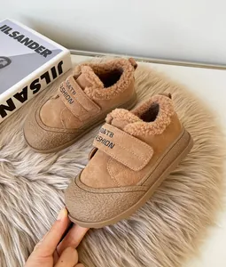 Macro view of brown fur-lined children's winter shoes with Velcro strap and textured sole.