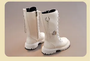 Detail der hohen Mädchenstiefel in Creme mit dekorativer Kette und Herzanhänger