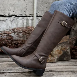 Gros plan sur des bottes hautes marron à bout pointu avec talons épais et boucles