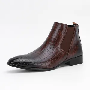Detailed side view of men's brown crocodile-texture Chelsea boots with black toe