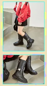 Detailansicht der hohen schwarzen Mädchenstiefel mit Herzanhänger und Kettenverzierung.