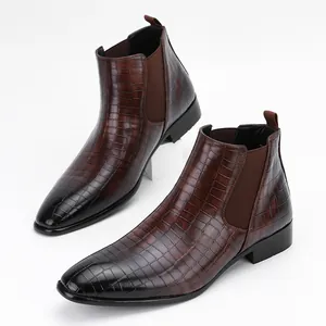Detailed view of men's brown crocodile embossed Chelsea boots on white background.