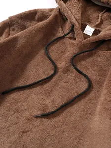 Detailopname van een zachte bruine koraalvlies hoodie met zwarte trekkoorden en label