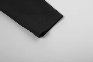 Détail de l'ourlet de manche à double couture sur une combinaison en maille noire.