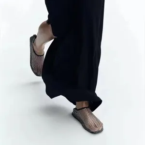 Primo piano di scarpe piatte in rete traforata nera con strass scintillanti su modella.