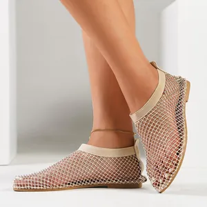 Dettaglio sandali piatti in rete beige con decorazioni di strass brillanti