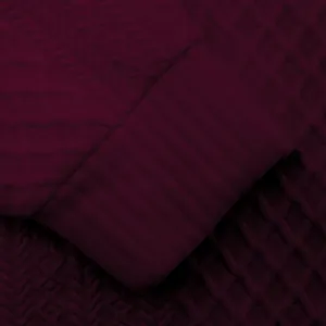 Primer plano de la tela jacquard burdeos de una sudadera de hombre y el puño de canalé