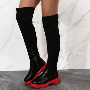 Vue détaillée de bottes hautes en maille noire avec semelles compensées rouges.