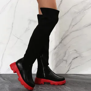 Gros plan sur des cuissardes pour femmes à semelle rouge épaisse et tricot noir