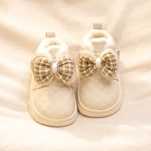 Close-up detail of warm baby girl winter cotton boots with plaid bows and soft fleece lining