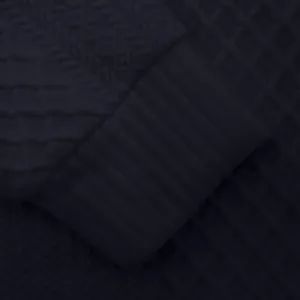 Detalle de primer plano del puño de canalé y textura jacquard en sudadera azul para hombre.